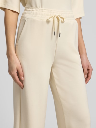 Kobiece modelka nosi Wide Leg Sweatpants mit elastischem Bund od Soyaconcept, jasny beż, gładka tekstura, materiał z dodatkiem modalu, z przodu sznurek, widok z przodu, zbliżenie na talię.