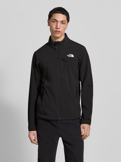 Męskimodel nosi Jacke mit Stehkragen und Logo von The North Face, czarna mieszanka materiałów z dodatkiem streczu, krój regular fit, zamek błyskawiczny, stójka, kieszenie zapinane na zamek błyskawiczny, logo, długość tyłu w rozmiarze M: 71 cm, szerokość ramion w rozmiarze M: 46 cm, szerokość klatki piersiowej w rozmiarze M: 56 cm, długość rękawów w rozmiarze M: 58 cm, gładka tekstura, prosty fason, minimalne detale, kolory: czarny, biel, całkowita widoczność z przodu