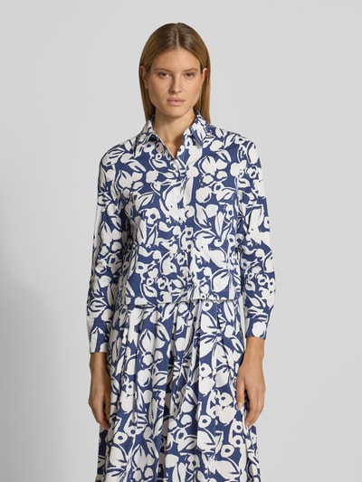 Kobiece modelka nosi Regular Fit Hemdbluse mit floralem Allover-Print von More & More, mieszanka bawełny elastycznej, krój regular fit, kwiatowy nadruk na całej powierzchni, kołnierzyk koszulowy, z długim rękawem, listwa guzikowa, długość tyłu w rozmiarze 36: 52 cm, długość rękawów w rozmiarze 36: 57 cm, odcienie niebieskiego i bieli, wzór kwiatowy, faktura gładka, Ganzkörperansicht z przodu.