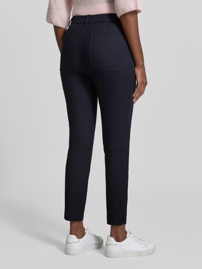 Modelka nosi Schmale Hose aus Baumwoll-Mix von Marc Cain, Mieszanka bawełny ekologicznej z dodatkiem streczu, krój slim fit, zapięcie na guzik i zamek błyskawiczny, Kieszenie z tyłu, Szerokość w rozmiarze 36: 38 cm, Długość wewnętrzna nogawki w rozmiarze 36: 71 cm, ciemnogranatowy kolor, gładka tekstura, Ganzkörperansicht Rückansicht