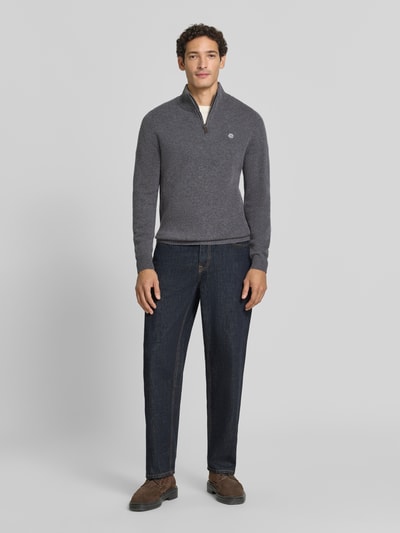 Männermodel trägt Regular Fit Strickpullover aus reiner Wolle von MCNEAL in Grau mit Logo-Stickerei, Troyer-Kragen, Ganzkörperansicht von vorne