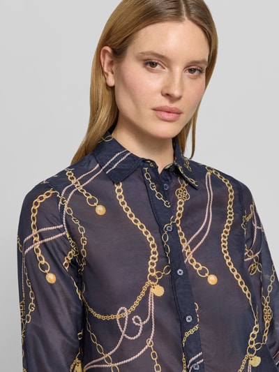 Kobiece modelka nosi Bluse mit Seide-Anteil und Kentkragen od Gant, wzór łańcuchów, bawełniany miks z domieszką jedwabiu, krój regular fit, kent kołnierzyk, zapięcie na guziki, sportowe mankiety, zaokrąglony dół, długość tyłu w rozmiarze 36: 68 cm, długość rękawa w rozmiarze 36: 61 cm, widok na górną część ciała z przodu.