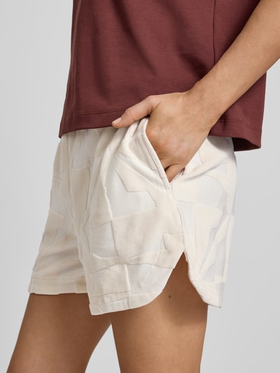 Kobiece modelka ma na sobie Bermudas mit elastischem Bund Modell 'NABI' od ICHI, bawełniany materiał w jasnych kolorach, luźny krój, szerokość w rozmiarze S: 38 cm, długość wewnętrzna nogawki S: 11 cm, zdjęcie z przodu, zbliżenie na biodra.
