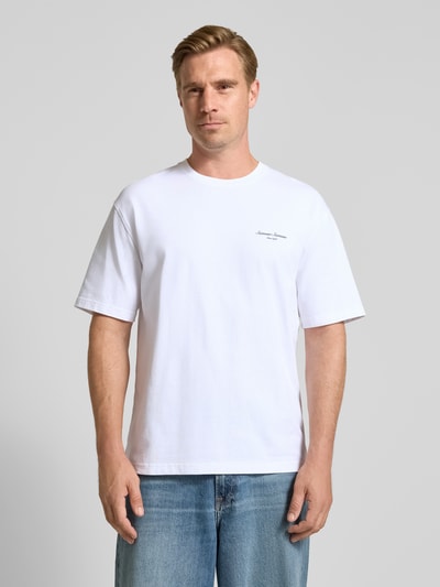 Männermodel trägt weißes T-Shirt mit Label-Stickerei Modell 'Sauni' von Samsøe Samsøe, gerader Schnitt, reine Baumwolle, Ganzkörperansicht von vorne.