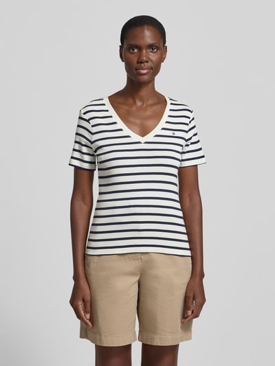 Frauenmodel trägt Slim Fit T-Shirt aus reiner Baumwolle von Tommy Hilfiger, efekt: jednolity kolor, krój slim fit, wyhaftowane logo, dekolt w serek, krótki rękaw, wykończenie materiału: dżersej, materiał: bawełna, Ganzkörperansicht von vorne.