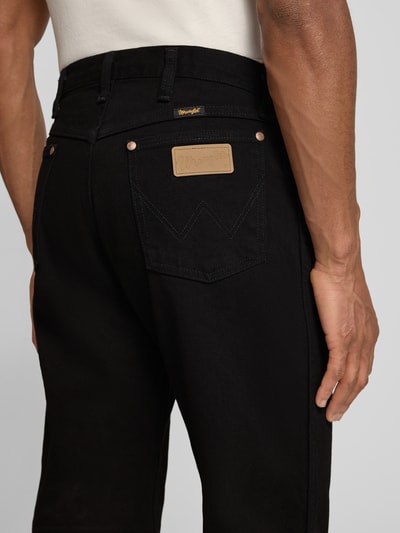 Männermodel trägt Cowboy Cut Jeans im 5-Pocket-Design von Wrangler, reine Baumwolle, schwarze Farbe, Detailaufnahme Rückansicht.