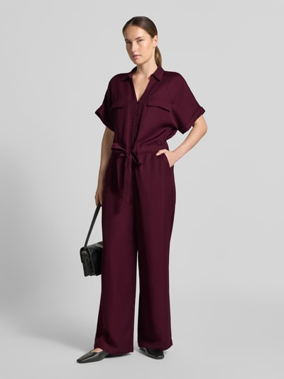 Frauenmodel trägt Jumpsuit aus Viskose-Lyocell-Mix von MORE in Dunkelrot mit Umlegekragen, Taillenband, Ganzkörperansicht von vorne. Kontext: Taillierte Passform, V-Ausschnitt mit Knopfleiste, Halbarm, angedeutete Brusttaschen, elastische Taillenpartie, Rückenlänge 49 cm, Brustweite 55 cm, Ärmellänge 33 cm, Gesamtlänge 152 cm, Innenbeinlänge 71 cm.
