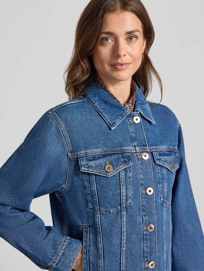 Kobiece model nosi kurtka jeansowa z bawełny, krój regular fit, Model 'Saima' od MOS MOSH, wykładany kołnierz, kieszenie na piersi, listwa guzikowa, niebieski odcień, tekstura dżinsu, zbliżenie na górną część ciała