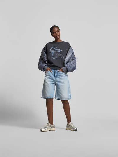 Frauenmodel trägt Regular Fit Sweatshirt mit Motiv-Print von Anine Bing in Dunkelgrau, Reine Baumwolle, Rundhalsausschnitt, Elastische Abschlüsse, Rückenlänge bei Größe S 59 cm, Ganzkörperansicht von vorne.