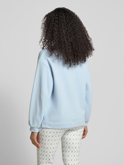 Frauenmodel trägt Relaxed Fit Sweatshirt mit Logo-Detail von Marc Cain in Hellblau, Baumwoll-Mix, elastische Ärmelabschlüsse, Ganzkörperansicht Rückansicht.