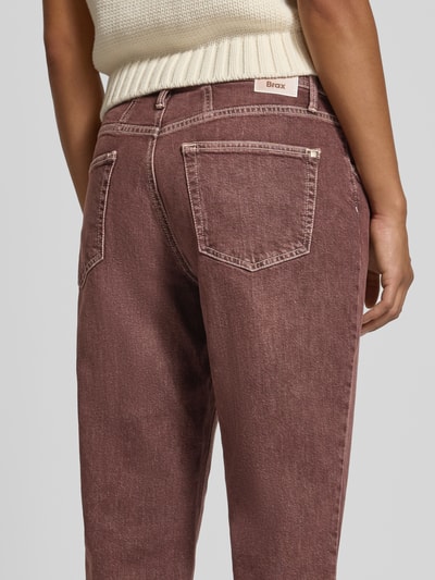 Frauenmodel trägt Tapered Fit Jeans aus Baumwoll-Mix Modell 'MILEY' von Brax in brauner Denim-Optik mit 5-Pocket-Design, Ganzkörperansicht Rückansicht.