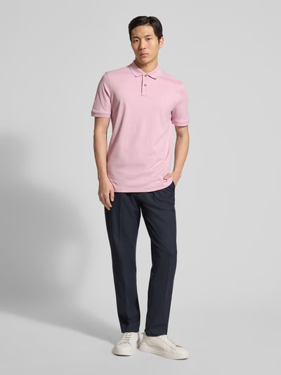 Männermodel trägt Regular Fit Poloshirt mit Logo-Stitching von Fynch-Hatton in Rosa, reine Baumwolle, Polokragen, Ganzkörperansicht von vorne.