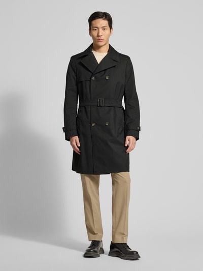 Męski model nosi Regular Fit Trenchcoat mit Reverskragen Modell 'Aberdeen' od CINQUE, czarny, z paskiem, krój regular fit, całkowity widok z przodu. Szerokość w rozmiarze 50: 44 cm, długość tyłu: 97 cm, szerokość klatki piersiowej: 45 cm, długość rękawa: 66 cm.