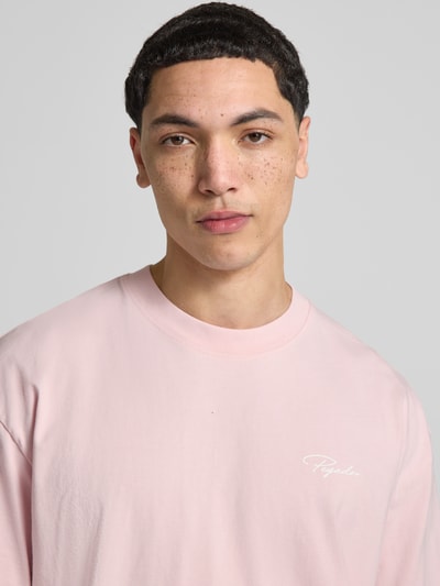 Mężczyzna nosi Oversized T-Shirt aus reiner Baumwolle Modell 'Pike' von Pegador, różowy, półrękawy, okrągły dekolt, detal z logo, Nahaufnahme Oberkörper.