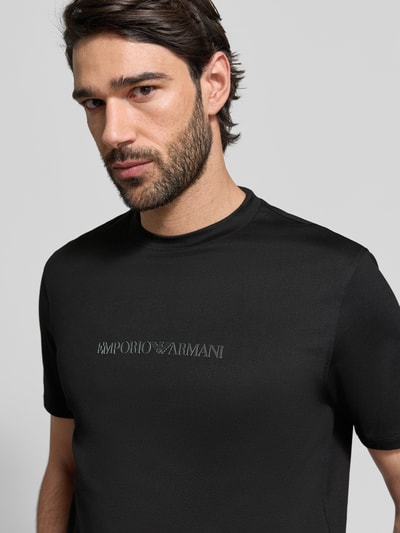 Männermodel trägt Regular Fit T-Shirt mit Logo-Detail von Emporio Armani in Schwarz, reine Baumwolle, Nahaufnahme Oberkörper.