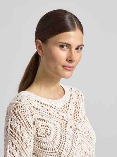 Frauenmodel trägt Strickshirt mit Rundhalsausschnitt von monari aus cremefarbenem Baumwoll-Mix im Ajourstrick, Nahaufnahme Oberkörper.