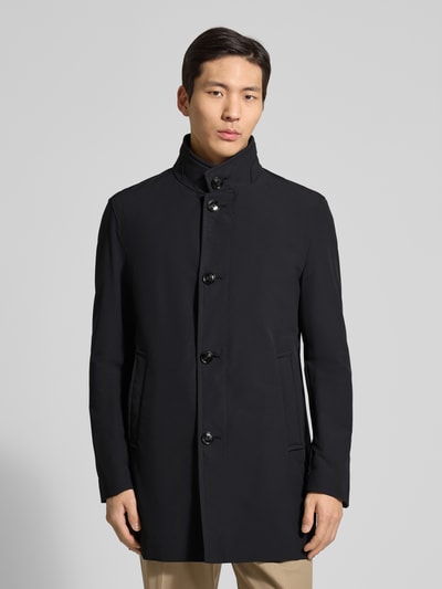 Męski model nosi Regular Fit Kurzmantel mit Stehkragen Modell 'FYNN' von Strellson, efekt: jednolity kolor, krój regular fit, stójka, listwa guzikowa, wyhaftowane logo, naszywka z logo, długi rękaw, wykończenie: rozcięcie, kieszeń napoleonka, wpuszczane kieszenie, wykończenie materiału: splot twill, Ganzkörperansicht von vorne.