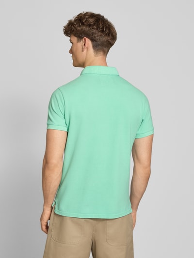 Männermodel trägt Regular Fit Poloshirt mit Logo-Stitching von Superdry in Mint, Reine Baumwolle, Polokragen, Kurzärmelig, Rückenlänge 67 cm, Ganzkörperansicht Rückansicht.