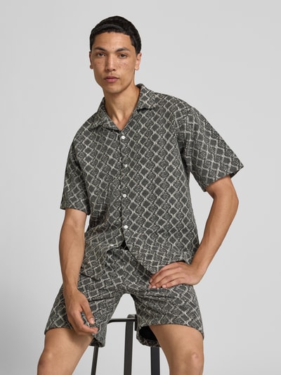 Männermodel trägt Boxy Fit Freizeithemd im Allover-Look Modell 'ZANDER' von Redefined Rebel, Reine Baumwolle, Reverskragen, Ganzkörperansicht von vorne. Rückenlänge bei Größe M: 65 cm, Schulterbreite bei Größe M: 51 cm, Ärmellänge bei Größe M: 25 cm.