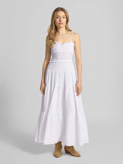 Frauenmodel trägt Midikleid mit Rüschen und Volantsaum von MICHAEL Michael Kors in Weiß, taillierter Schnitt, Karree-Ausschnitt, Ganzkörperansicht von vorne.