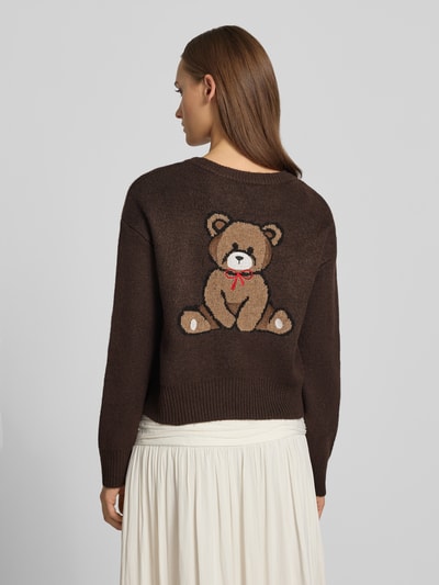 Frauenmodel trägt Relaxed Fit Strickpullover mit Stickerei Modell 'TEDDY' von ONLY, braun mit Bär-Motiv, Damen Strickjacke, Ganzkörperansicht Rückansicht.
