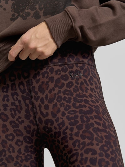 Vrouwenmodel draagt Leggings aus Viskose-Mix van Lala Berlin, bruin-zwart luipaardpatroon, label-print, elastische tailleband, visgraatstructuur, detailopname heupen.