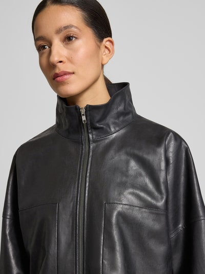 Vrouwenmodel draagt Drykorn Blazer met Stehkragen Model 'ELSTOW' in zwart leerlook met ritssluiting en steekzakken, nahaufnahme bovenlichaam.