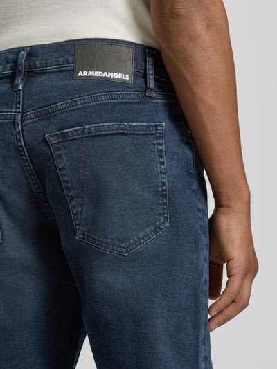Mannenmodel draagt donkerblauwe tapered fit jeans uit katoen-lyocellmix, AARJO TARPA van ARMEDANGELS, detailopname achterkant.