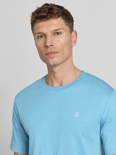 Männermodel trägt Regular Fit T-Shirt aus reiner Baumwolle von Marc O’Polo, unifarbenes hellblau, Logo-Stitching, Nahaufnahme Oberkörper.