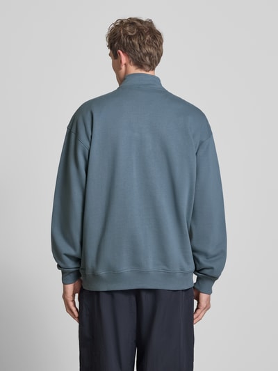 Männermodel trägt Relaxed Fit Sweatshirt mit Stehkragen und Reißverschluss von The North Face in Blau, strukturierte Baumwolle, Ganzkörperansicht Rückansicht.