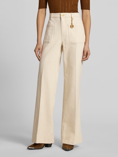 Frauenmodel trägt High Rise Bootcut Fit Stoffhose aus Baumwoll-Mix von MICHAEL Michael Kors in Beige mit aufgesetzten Eingrifftaschen, Label-Anhänger in metallic, weit geschnittenes Bein, Struktur fein, Nahaufnahme Oberkörper.