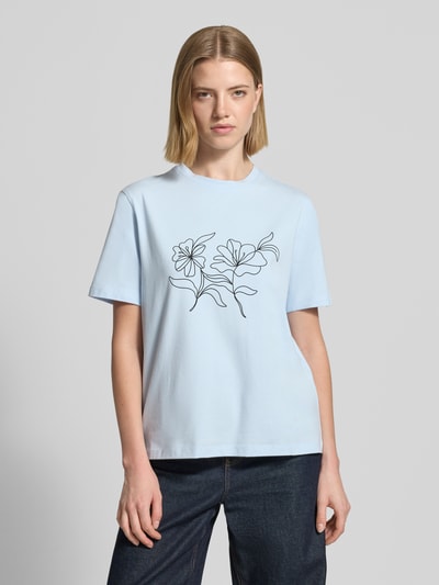 Frauenmodel trägt T-Shirt mit geripptem Rundhalsausschnitt Modell 'NORA' von Vila, hellblau, lockerer Schnitt, florales Linienmuster, Baumwoll-Elasthan-Mix, Ganzkörperansicht von vorne.