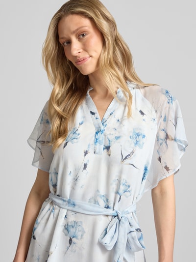 Frauenmodel trägt Knielanges Kleid mit Serafino-Kragen von More & More aus Chiffon, Taillierter Schnitt, Bindegürtel, Schmetterlingsärmel, florales Muster, Rückenlänge 102 cm, Brustweite 42 cm, Ärmellänge 28 cm, Nahaufnahme Oberkörper.