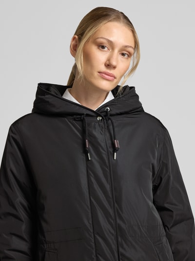 Kobiece model nosi Regular Fit Parka mit Kapuzenkragen od Marc O'Polo, czarny kolor, gładka tekstura, zbliżenie na górną część ciała.