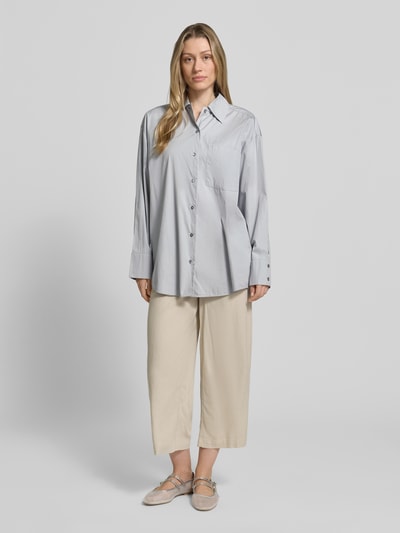 Frauenmodel trägt Oversized Hemdbluse aus reiner Baumwolle von Marc O'Polo in Unifarbe mit Kentkragen und Brusttasche, Ganzkörperansicht von vorne.