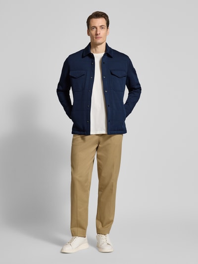 Männermodel trägt Regular Fit Sweatjacke aus Baumwoll-Mix von Tommy Hilfiger in Dunkelblau mit Druckknopfleiste, unifarben, Ganzkörperansicht von vorne.