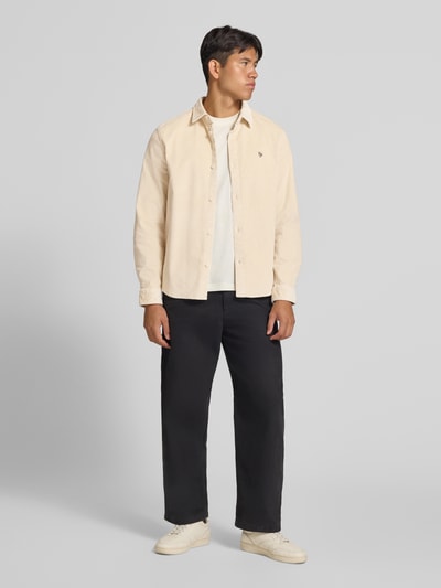 Männermodel trägt Slim Fit Cordhemd aus Baumwoll-Mix von REVIEW in Beige mit Ripp-Optik und Logo-Prägung, Ganzkörperansicht von vorne