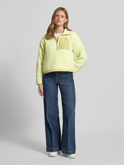 Frauenmodel trägt Regular Fit Sweatshirt mit Stehkragen Modell 'Yumiori' von The North Face in Gelb, Teddyfell, Brusttasche, Logo-Stitching, Ganzkörperansicht von vorne