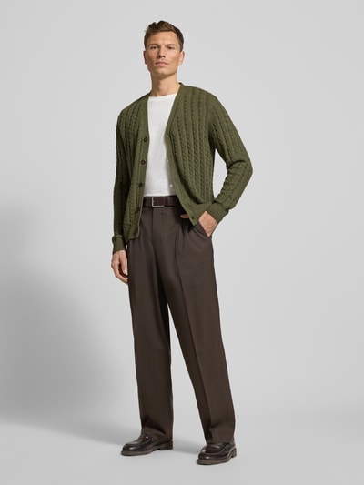 Männermodel trägt Strickjacke aus Baumwoll-Woll-Mix von Fynch-Hatton in Olivgrün, Lockerer-Schnitt, Gerippte-Abschlüsse, V-Ausschnitt, Knopfleiste, Ganzkörperansicht von vorne. Rückenlänge bei Größe M: 70 cm, Ärmellänge bei Größe M: 75 cm.
