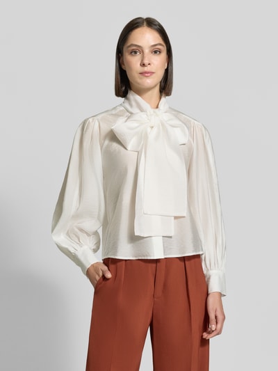 Frauenmodel trägt Regular Fit Langarmbluse aus Lyocell-Mix von Jake*s Collection in Creme mit seidigem Glanz, weiten Ärmeln und großer Schleife, Nahaufnahme Oberkörper.