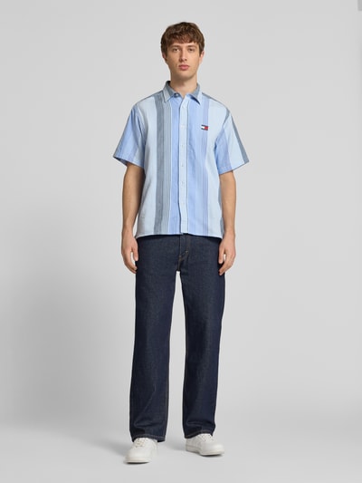 Männermodel trägt Relaxed Fit Freizeithemd aus reiner Baumwolle von Tommy Jeans, Optik:Allover-Muster, gestreift, Ganzkörperansicht von vorne.