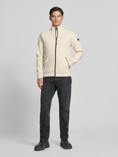 Männermodel trägt Sweatjacke mit Label-Patches und Stehkragen von PME Legend, cremefarben, Reißverschluss, seitliche Taschen, Ganzkörperansicht von vorne. Baumwoll-Mix mit Stretch-Anteil, Straight Fit, gerippte Abschlüsse, Rückenlänge 73 cm, Ärmellänge 68 cm.
