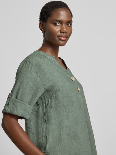 Frauenmodel trägt Relaxed Fit Leinenbluse mit V-Ausschnitt Modell 'Is44sii' von ZABAIONE, grünes reines Leinen, Knopfleiste, regulierbare Ärmellänge, Nahaufnahme Oberkörper.
