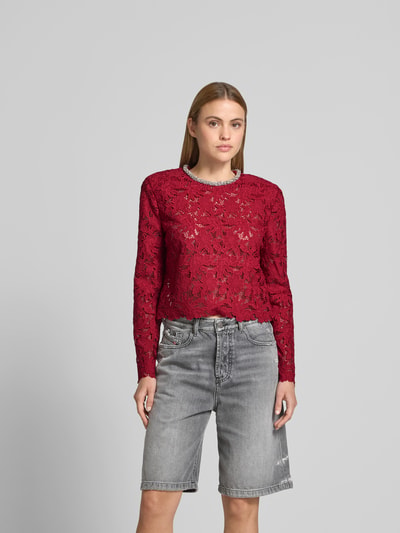 Frauenmodel trägt Slim Fit Longsleeve aus floraler Spitze von Self-Portrait in Rot mit Ziersteinbesatz, semitransparent, Baumwolle, Ganzkörperansicht von vorne.