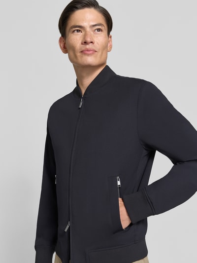Männermodel trägt Boxy Fit Bomberjacke mit Viskose-Anteil Modell 'Hanry BMB' von BOSS, dunkel und glatt, Nahaufnahme Oberkörper, Herren Bomberjacke von BOSS.