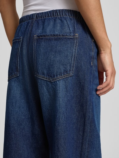 Kobieta nosi Loose Fit Jeans mit weitem Bein od REVIEW, czysty bawełna, krój loose fit, szerokie nogawki, elastyczny pas, widok z tyłu, zbliżenie na biodra