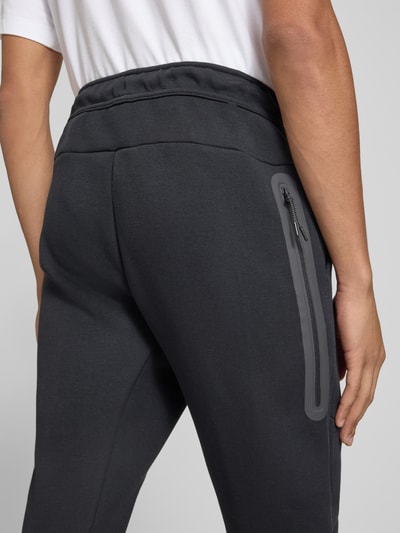 Männermodel trägt Slim Fit Sweathose aus Baumwoll-Mix von Nike in Dunkelgrau, glatte Struktur, Detailaufnahme Rücken, Herren Sweathose von Nike.