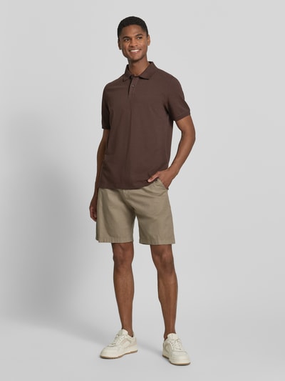 Męski model nosi Regular Fit Poloshirt aus reiner Baumwolle von s.Oliver RED LABEL, efekt: jednolity kolor, krój regular fit, wyhaftowane logo, kołnierzyk polo, dekolt w serek, listwa guzikowa, krótki rękaw, zakończenie rękawów: prążkowane, wykończenie: z rozcięciami po bokach, wykończenie materiału: pika, bawełna. Ganzkörperansicht z przodu.