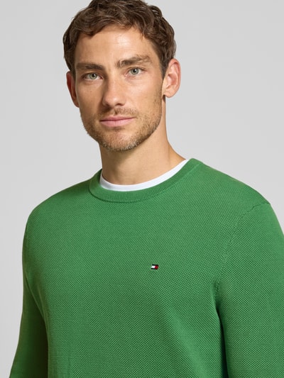 Mężczyznamodel nosi Regular Fit Pullover aus reiner Baumwolle od Tommy Hilfiger w kolorze zielonym, drobna struktura, zbliżenie na górną część ciała.