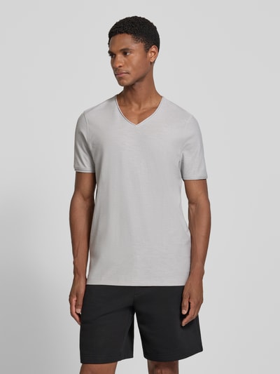 Męski model nosi t-shirt z dekoltem w serek i zrolowanym brzegiem od MCNEAL, bawełna, krój regular fit, długość tyłu 81 cm, jasnoszary, gładka tekstura, pełny widok z przodu.